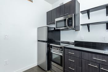 A modern kitchen with a stainless steel refrigerator, oven, and microwave. at RiDE at RiNo Apartments, Denver, Colorado